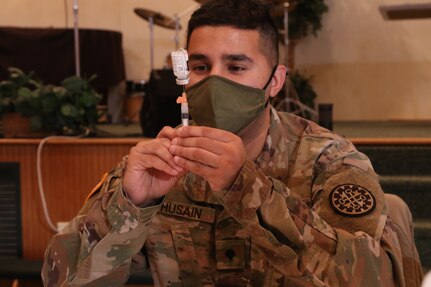 U.S. Army Spc. Mustansir Husain with the Task Force Spartan COVID Vaccination Testing Team, Michigan Army National Guard, prepares a COVID-19 vaccination in Lake Ann, Michigan, Jan. 21, 2021. The state of Michigan Department of Health and Human Services (MDHHS) requested support for the COVID-19 vaccine inoculations statewide.