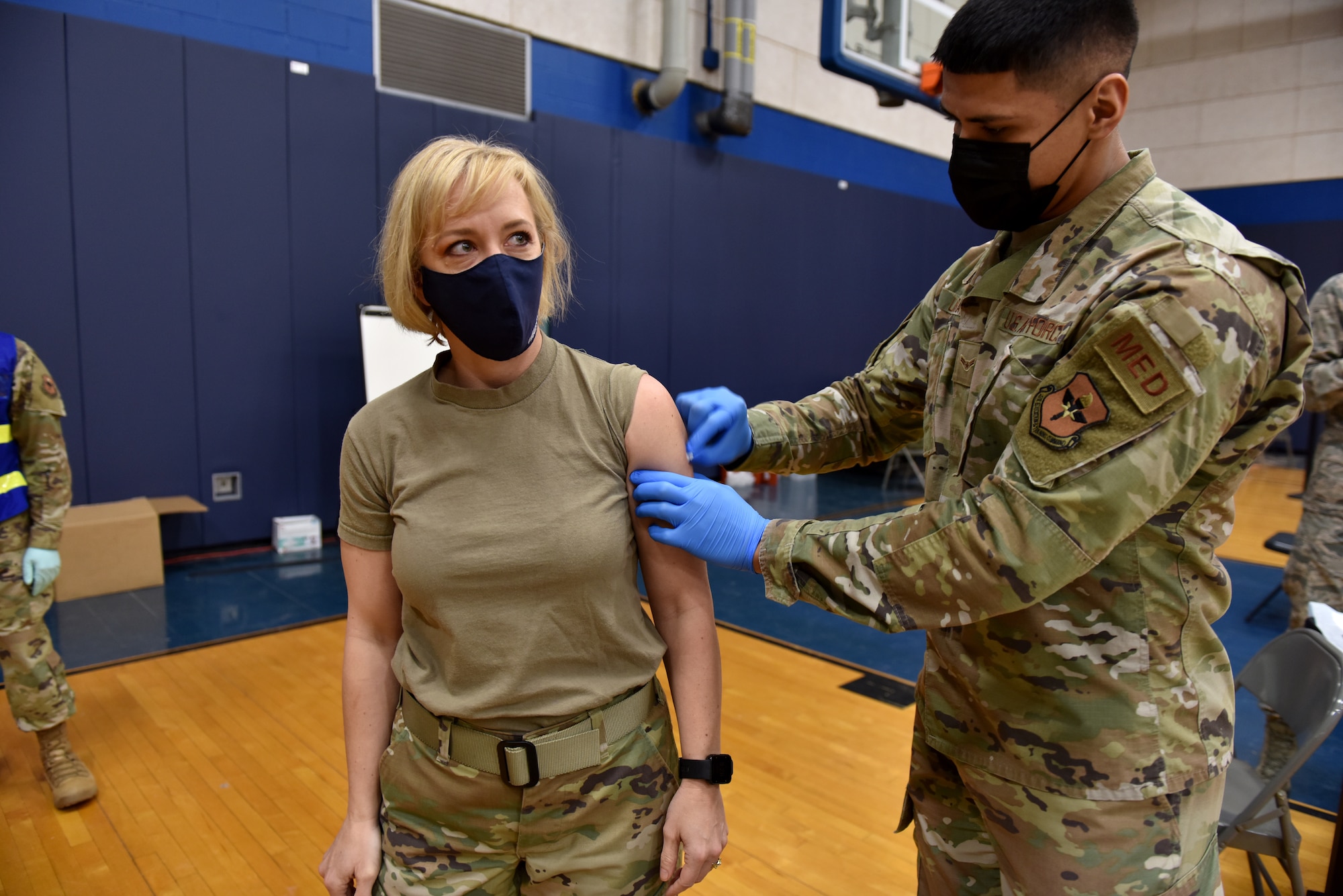 U.S. Air Force Chief Master Sgt. Casy Boomershine, 17th Training Wing command chief, watches as Airman 1st Class Benjamin Loera, 17th Operational Medical Readiness Squadron medical technician for active duty, prepares her arm for the COIVD-19 vaccine at the Mathis Fitness Center on Goodfellow Air Force Base, Texas, Jan. 22, 2021. On Jan. 20, Team Goodfellow vaccinated its frontline and mission essential positions and those who are considered high risk first, in accordance with the Department of the Air Forces distribution plan. (U.S. Air Force photo by Staff Sgt. Seraiah Wolf)