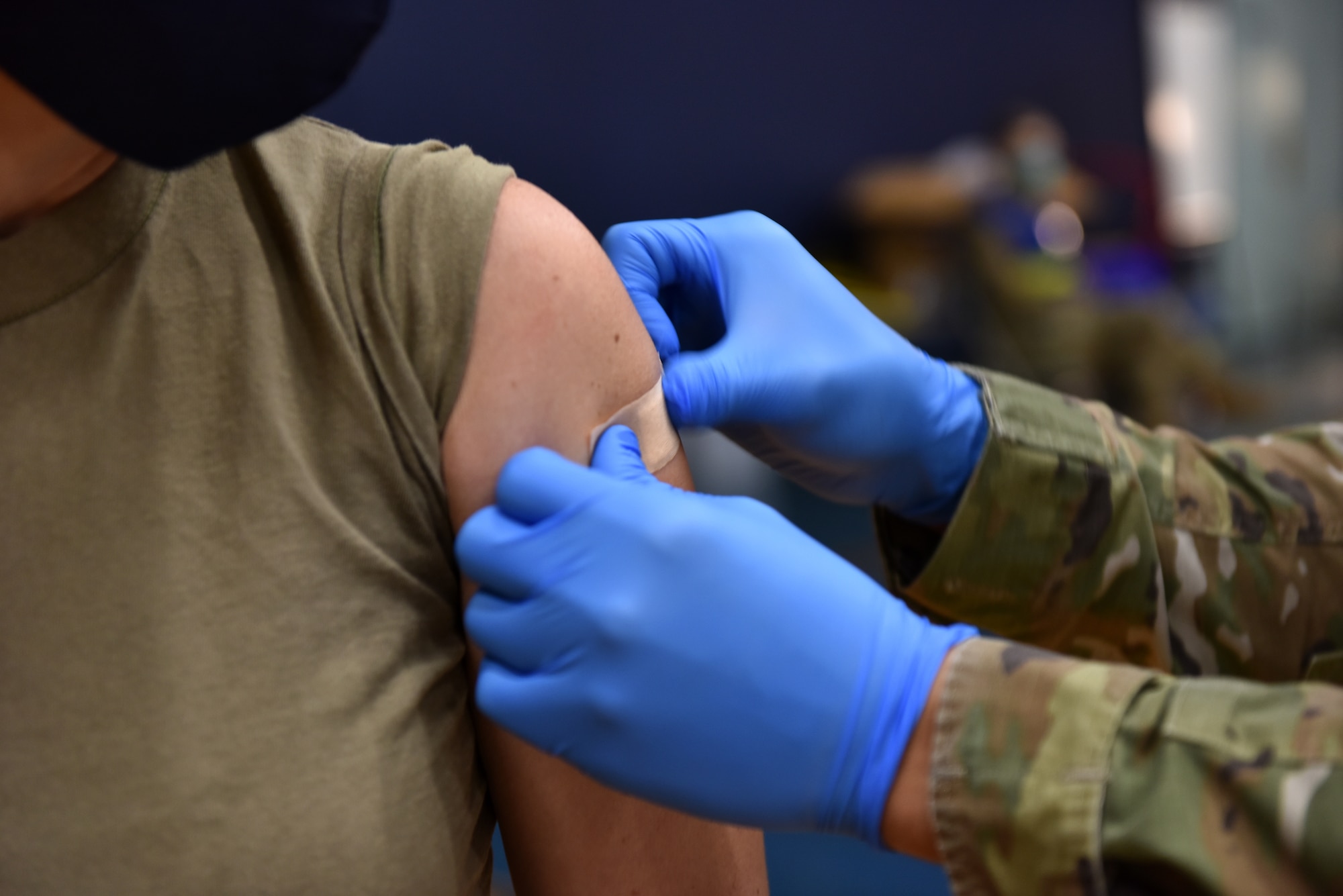 U.S. Air Force Airman First Class Benjamin Loera, 17th Operational Medical Readiness Squadron medical technician for active duty, applies a band aide to Chief Master Sgt. Casy Boomershine’s, 17th Training Wing command chief, arm after administering the COVID-19 vaccine at Mathis Fitness Center on Goodfellow Air Force Base, Texas, Jan. 22, 2021. On Jan. 20, Team Goodfellow vaccinated its frontline and mission essential positions and those who are considered high risk first, in accordance with the Department of the Air Forces distribution plan. (U.S. Air Force photo by Staff Sgt. Seraiah Wolf)