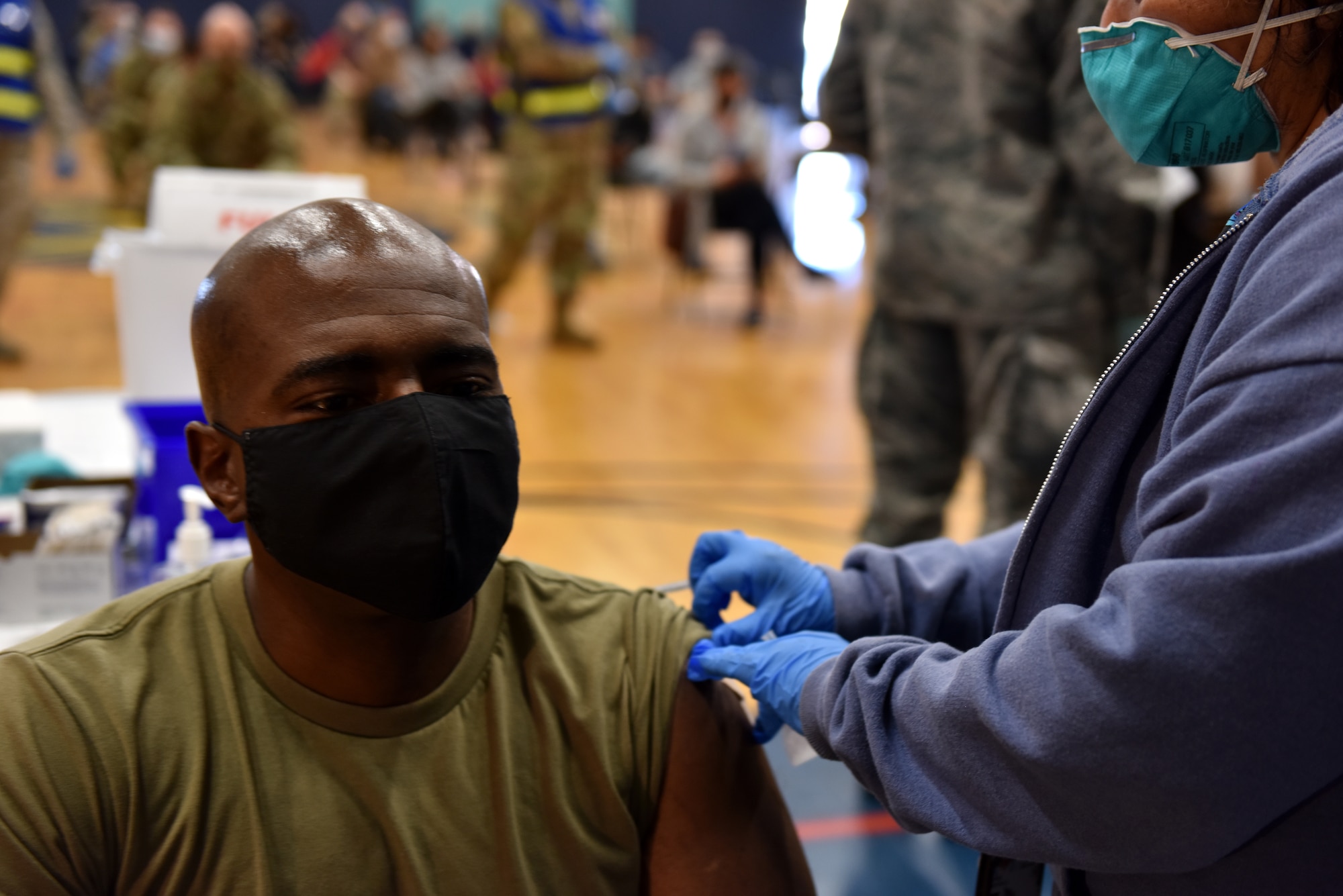A medical technician with the 17th Medical Group, applies a band aide to U.S. Air Force Col. James Finlayson, 17th Training Wing vice commander, after administering the COVID-19 vaccine at the Mathis Fitness Center on Goodfellow Air Force Base, Texas, Jan. 22,2021. On Jan. 20, Team Goodfellow vaccinated its frontline and mission essential positions and those who are considered high risk, first, in accordance with the Department of the Air Forces distribution plan. (U.S. Air Force photo by Staff Sgt. Seraiah Wolf)