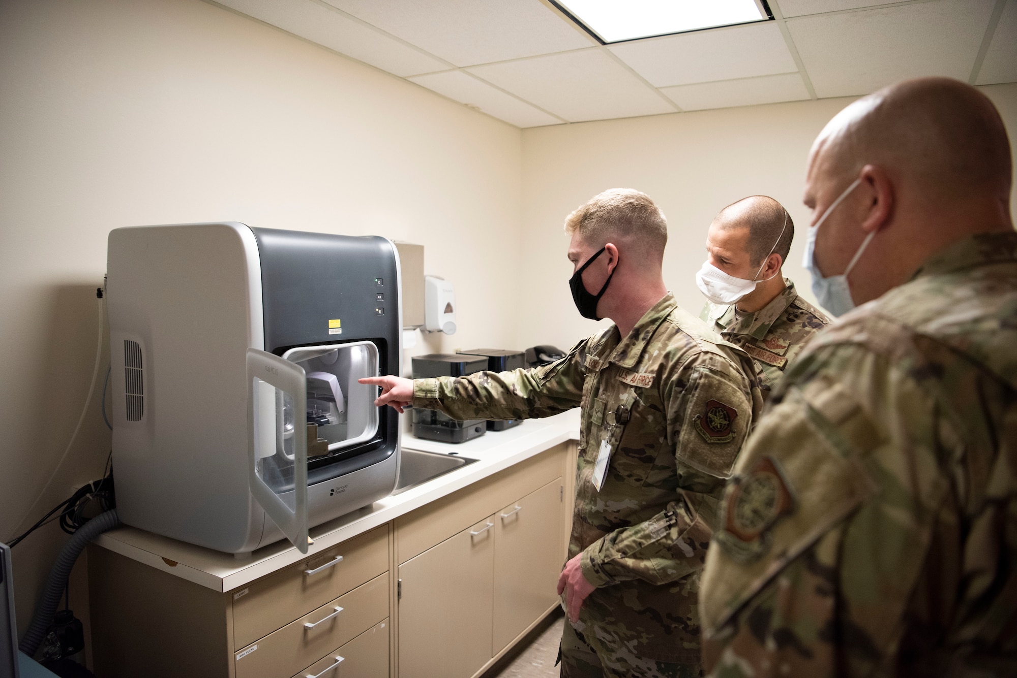 U.S. Air Force Airman 1st Class Colby Locke, center, 60th Dental Squadron dental laboratory technician, shows Col. Zachery Jiron, right, 60th Air Mobility Wing vice commander, and Chief Master Sgt. Robert Schultz, left, 60th AMW command chief, the MC-X5 milling unit that manufactures materials for a crown inside David Grant USAF Medical Center during Leadership Rounds Jan. 22, 2021, at Travis Air Force Base, California. The Leadership Rounds program provides 60th AMW leadership an opportunity to interact with Airmen and receive a detailed view of each mission performed at Travis AFB. (U.S. Air Force photo by Airman 1st Class Alexander Merchak)