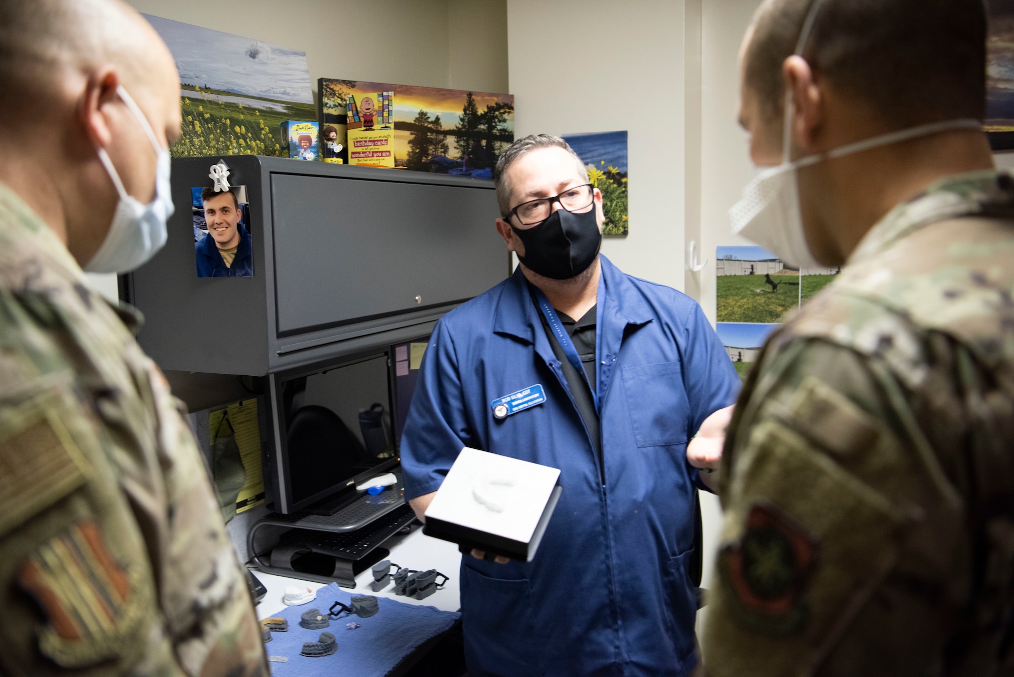 Robert Silva, center, 60th Dental Squadron dental laboratory technician, presents a finished cast to Col. Zachery Jiron, right, 60th Air Mobility Wing vice commander, and Chief Master Sgt. Robert Schultz, left, 60th AMW command chief, inside David Grant USAF Medical Center during Leadership Rounds Jan. 22, 2021 at Travis Air Force Base, California. The Leadership Rounds program provides 60th AMW leadership an opportunity to interact with Airmen and receive a detailed view of each mission performed at Travis AFB. (U.S. Air Force photo by Airman 1st Class Alexander Merchak)