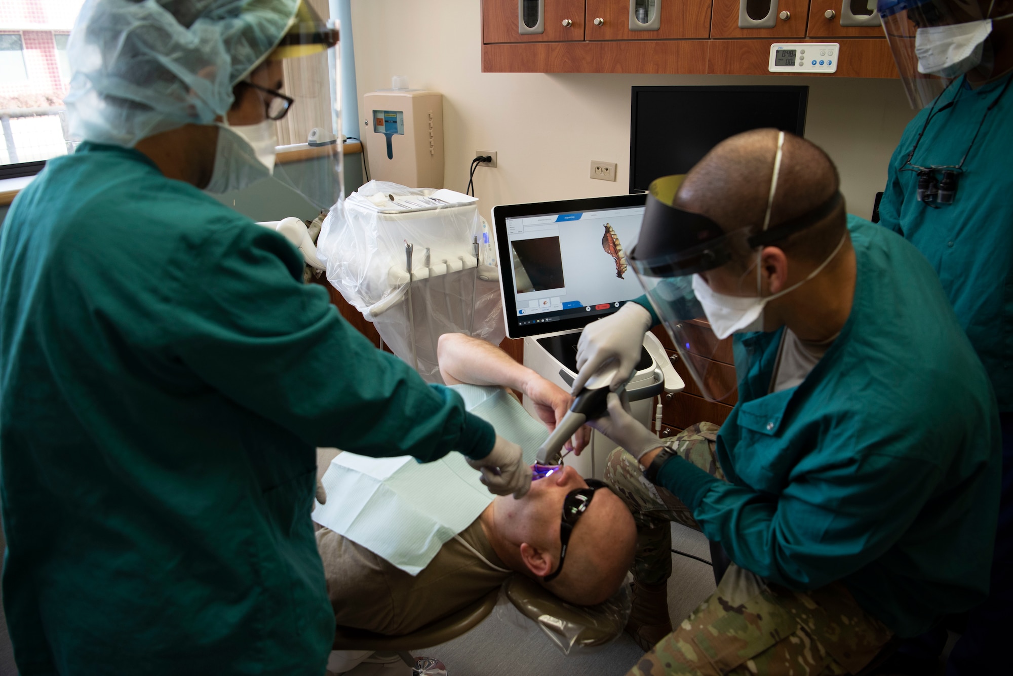 U.S. Air Force Senior Airman Francis Raymundo, left, 60th Dental Squadron dental technician, assists Col. Zachery Jiron, right, 60th Air Mobility Wing vice commander, as he performs an intra-oral scan on Chief Master Sgt. Robert Schultz, 60th AMW command chief, in the dental clinic of David Grant USAF Medical Center during Leadership Rounds Jan. 22, 2021, at Travis Air Force Base, California. The Leadership Rounds program provides 60th AMW leadership an opportunity to interact with Airmen and receive a detailed view of each mission performed at Travis AFB. (U.S. Air Force photo by Airman 1st Class Alexander Merchak)