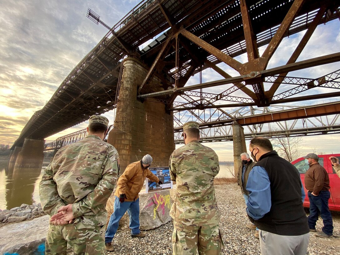 IN THE PHOTOS, Project Manager Mark Mazzone briefs Memphis District Commander Col. Zachary Miller and other district leadership on the details of the Hopefield project at the exact site where the armoring took place. Afterward, the group walked down to the riverbank to cut the ribbon, symbolizing the victory and celebration of completing yet another significant project. (USACE photos by Jessica Haas)