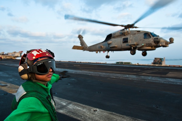 Airman Joyce Cruz checks for a clear deck before signaling to an MH-60R Sea Hawk to take off from the Nimitz-class aircraft carrier USS John C. Stennis (CVN 74).