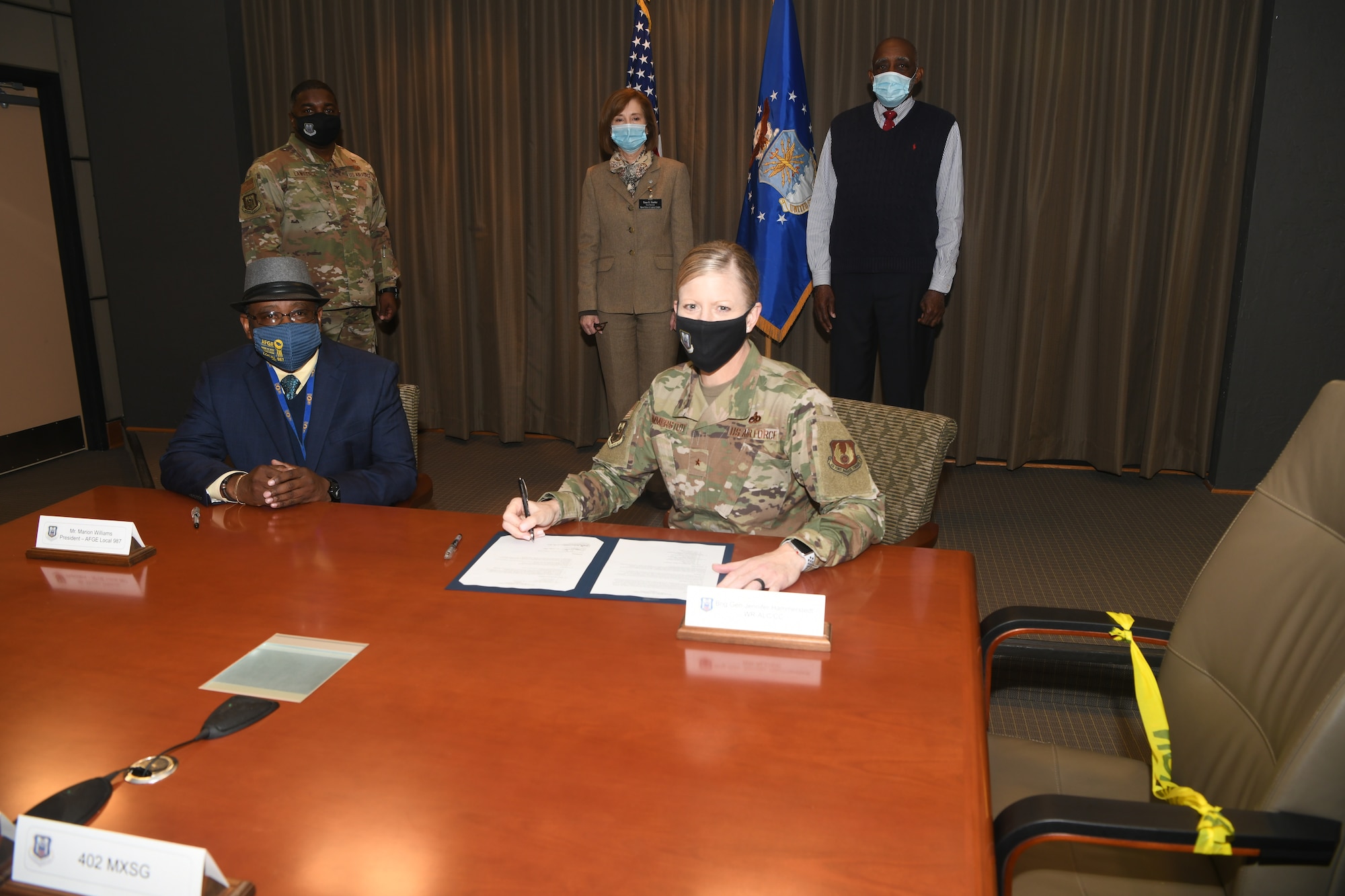 Photo shows man and woman sitting at table signing papers.