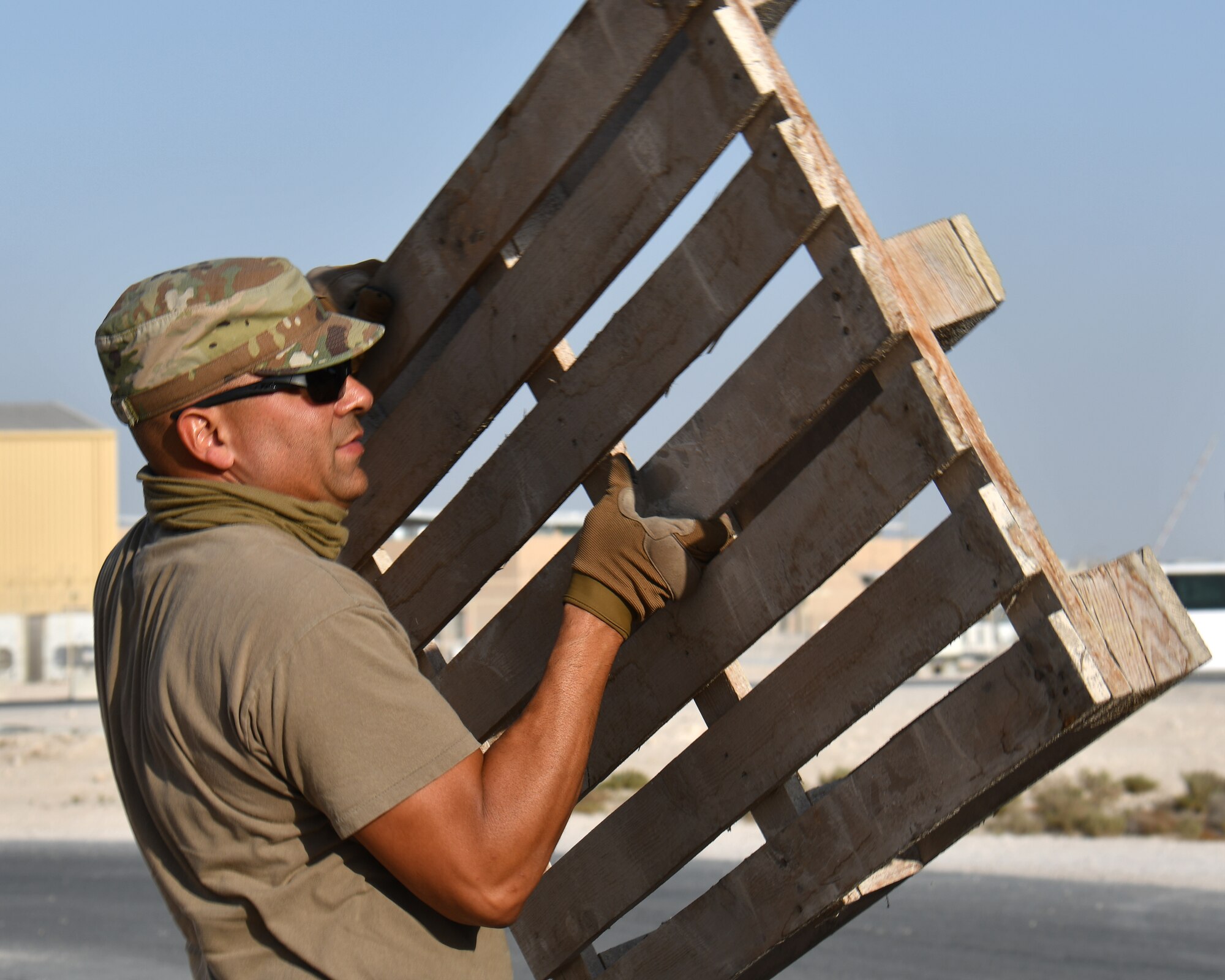 Airman carrying wooden pallet.