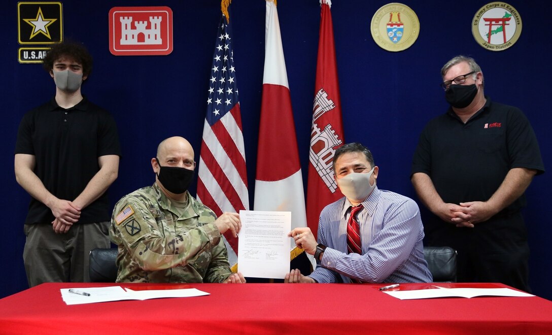 Col. Thomas J. Verell, Japan Engineer District commander, and Henry LeFebre, Zama Middle High School principal, display the 2021 Memorandum of Understanding between JED and ZMHS. The memorandum underscores the importance of the core curriculums of Science, Technology, Engineering, and Math and proclaims the Engineer District's intent to mentor students whose parents are station abroad.