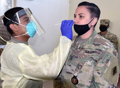 Pvt. Daniel Flores with Company A, 232nd Medical Battalion, uses a cotton swap to test Staff Sgt. Nicole Conti with Company A, 188th Medical Battalion, for COVID-19.