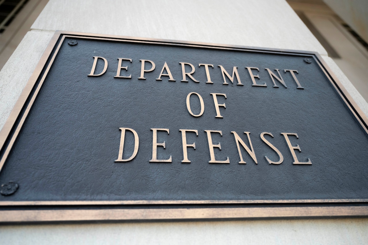 A metal placard reading "DEPARTMENT OF DEFENSE" is displayed on a building facade.