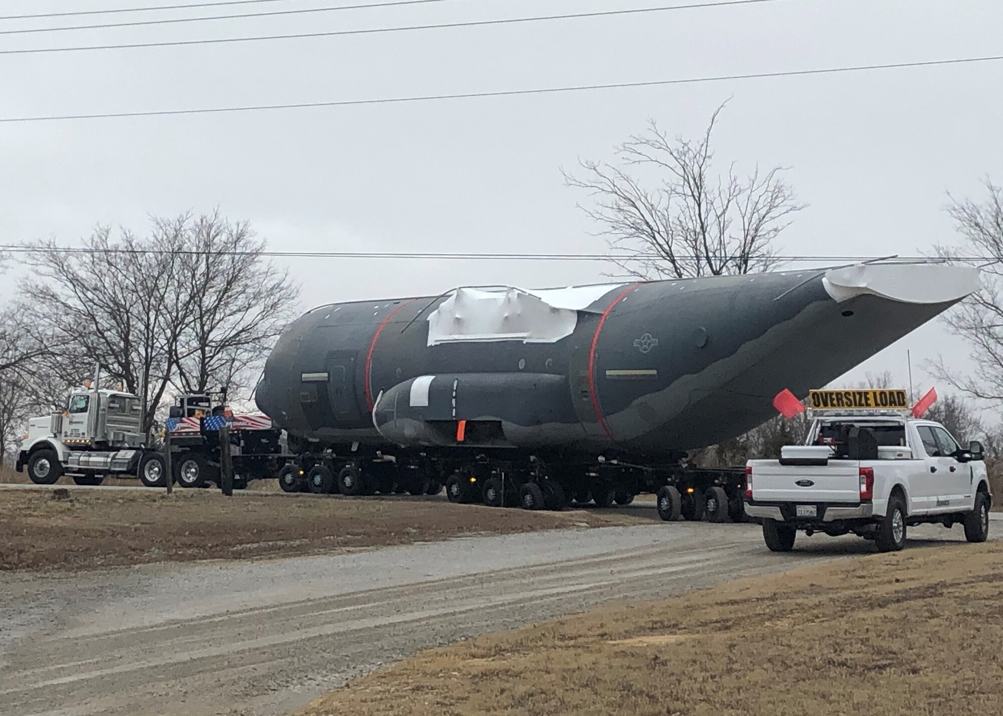C-130 aircraft body being towed on flatbed trailer