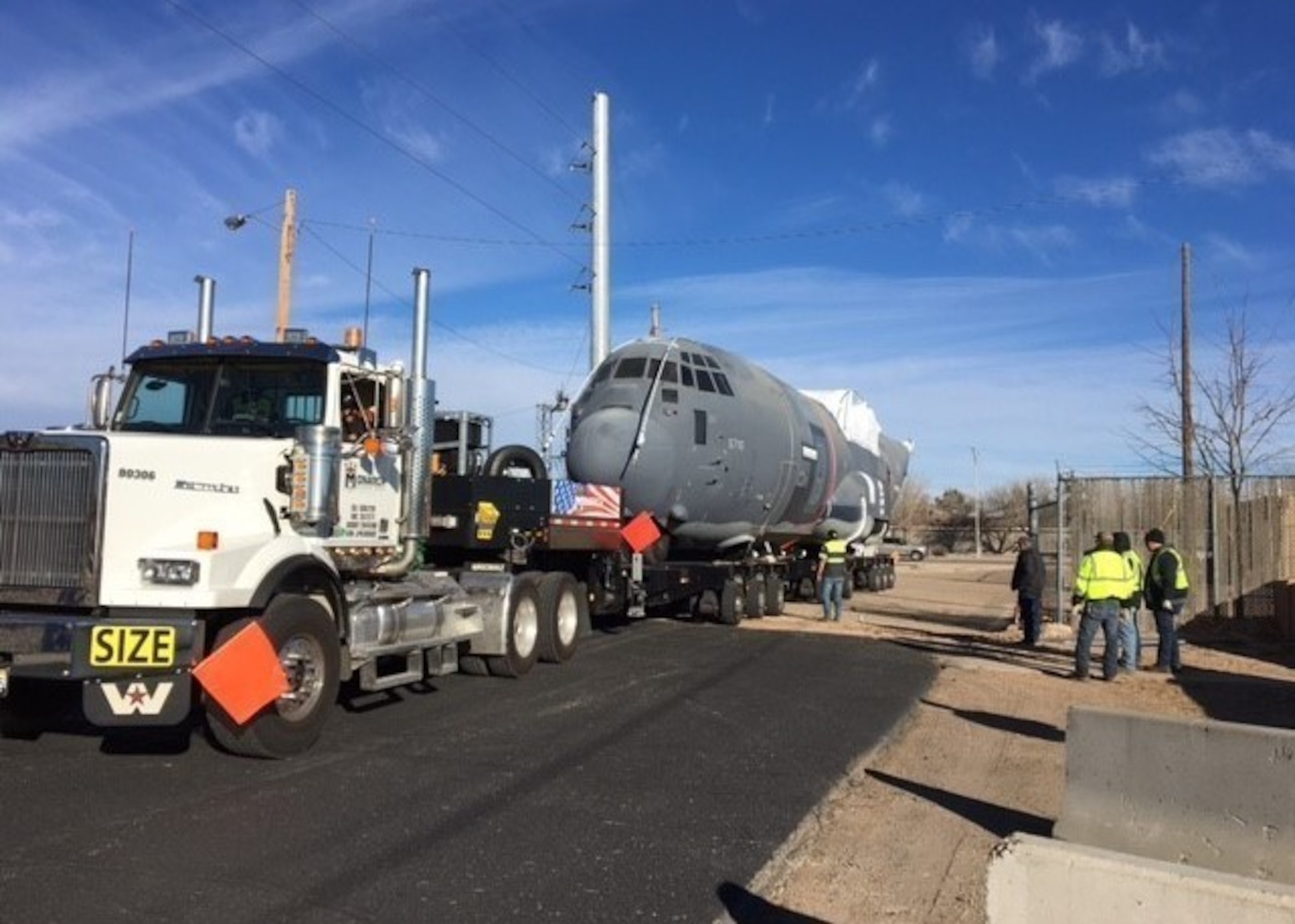 C-130 aircraft fuselage being towed on a flatbed trailer