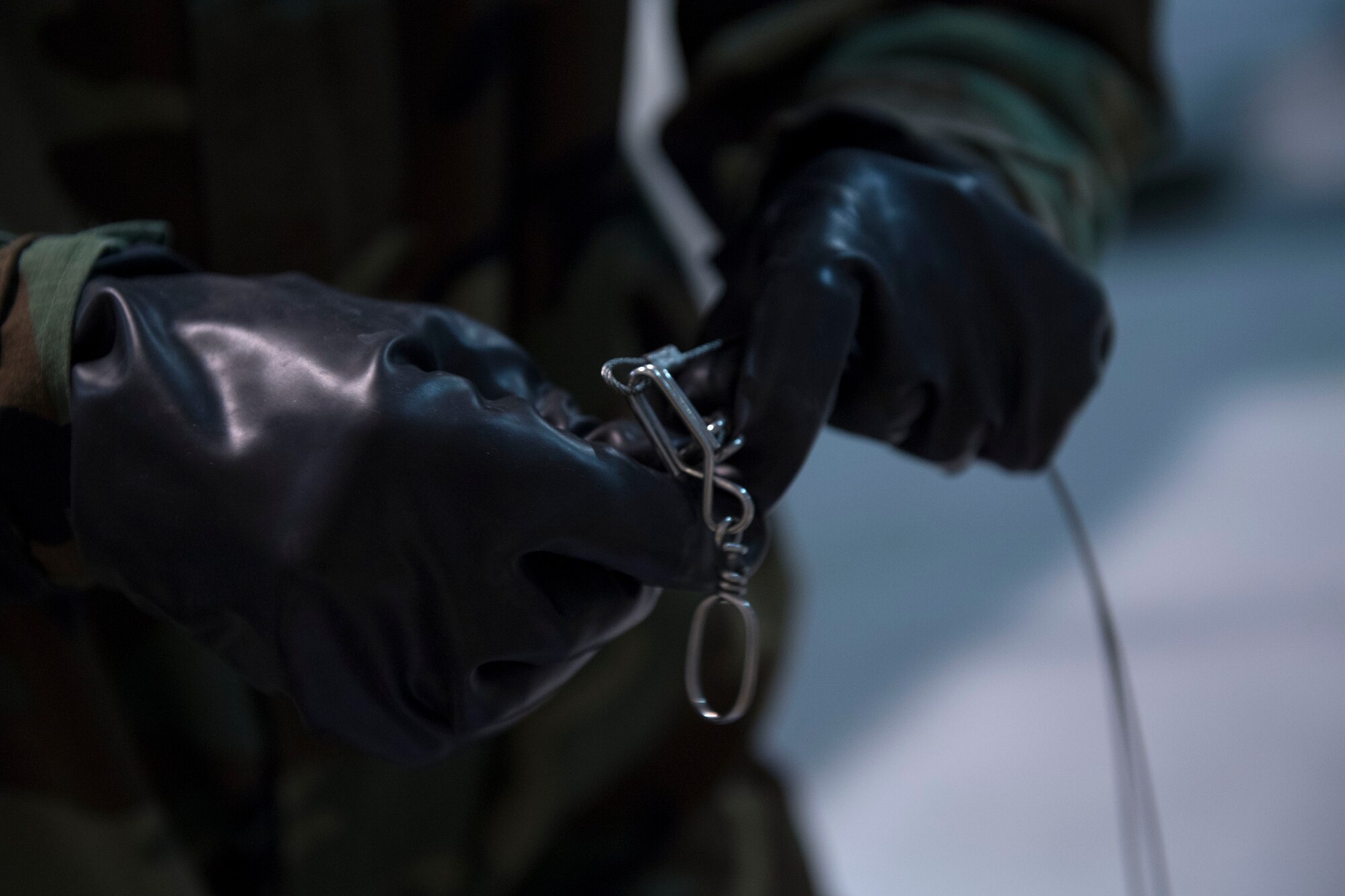 An US Air Force member prepares arming wire while wearing chemical, biological, radiological and nuclear equipment.