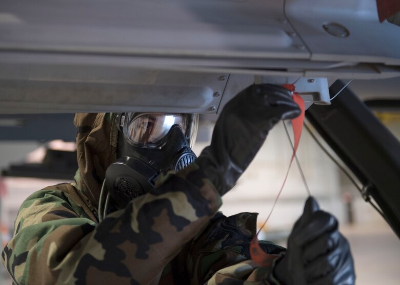 An US Airforce member threads arming wire while wearing chemical, biological, radiological and nuclear equipment.
