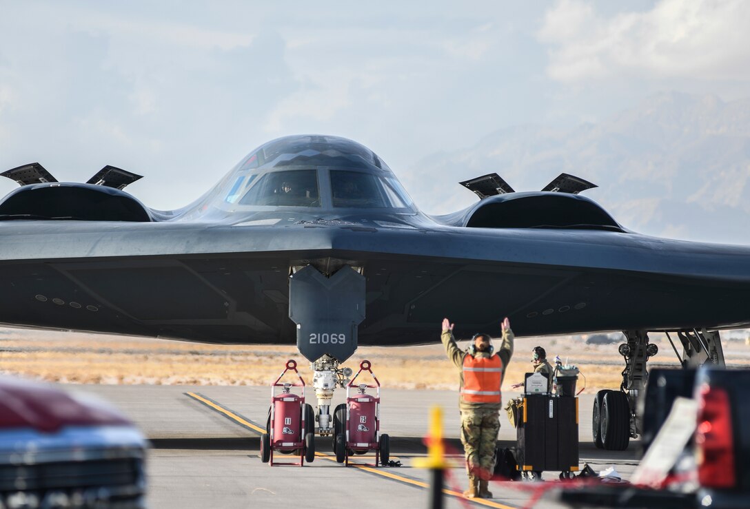 A 393rd Expeditionary Bomb Squadron crew chief guides a B-2 Spirit Stealth Bomber to a parking place during Red Flag 21-1, at Nellis Air Force Base, Nevada, Jan. 22, 2021. Well-trained Airmen are an important component to readiness and RF 21-1 prepare Airmen for future threats through experience in realistic combat scenarios. (U.S. Air Force photo by Staff Sgt. Sadie Colbert)