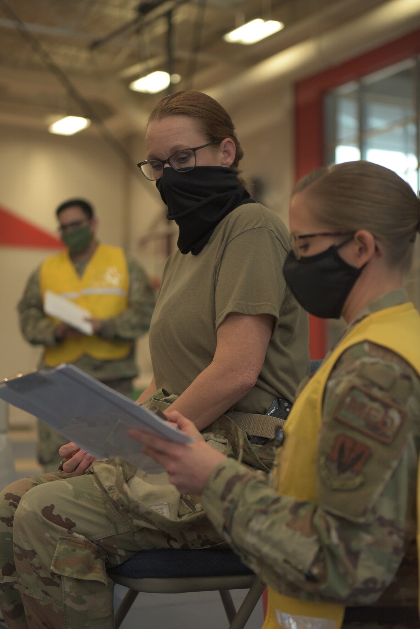 U.S. Air Force Chief Master Sgt. Kati Grabham, 325th Fighter Wing command chief, left, and Tech. Sgt. Haley Lecomte, 325th Operational Medical Readiness Squadron technician, right, discuss the Coronavirus vaccine prior administration at Tyndall Air Force Base, Florida, Jan. 21, 2021. Each individual who received the vaccine was pre-briefed on what they could expect to experience at the sight of the injection which could include muscle stiffness. (U.S. Air Force photo by Staff Sgt. Magen M. Reeves)