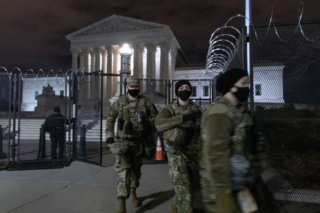 Guardsmen in front of the Supreme Court building on Capitol Hill make their way outside of the perimeter fencing.