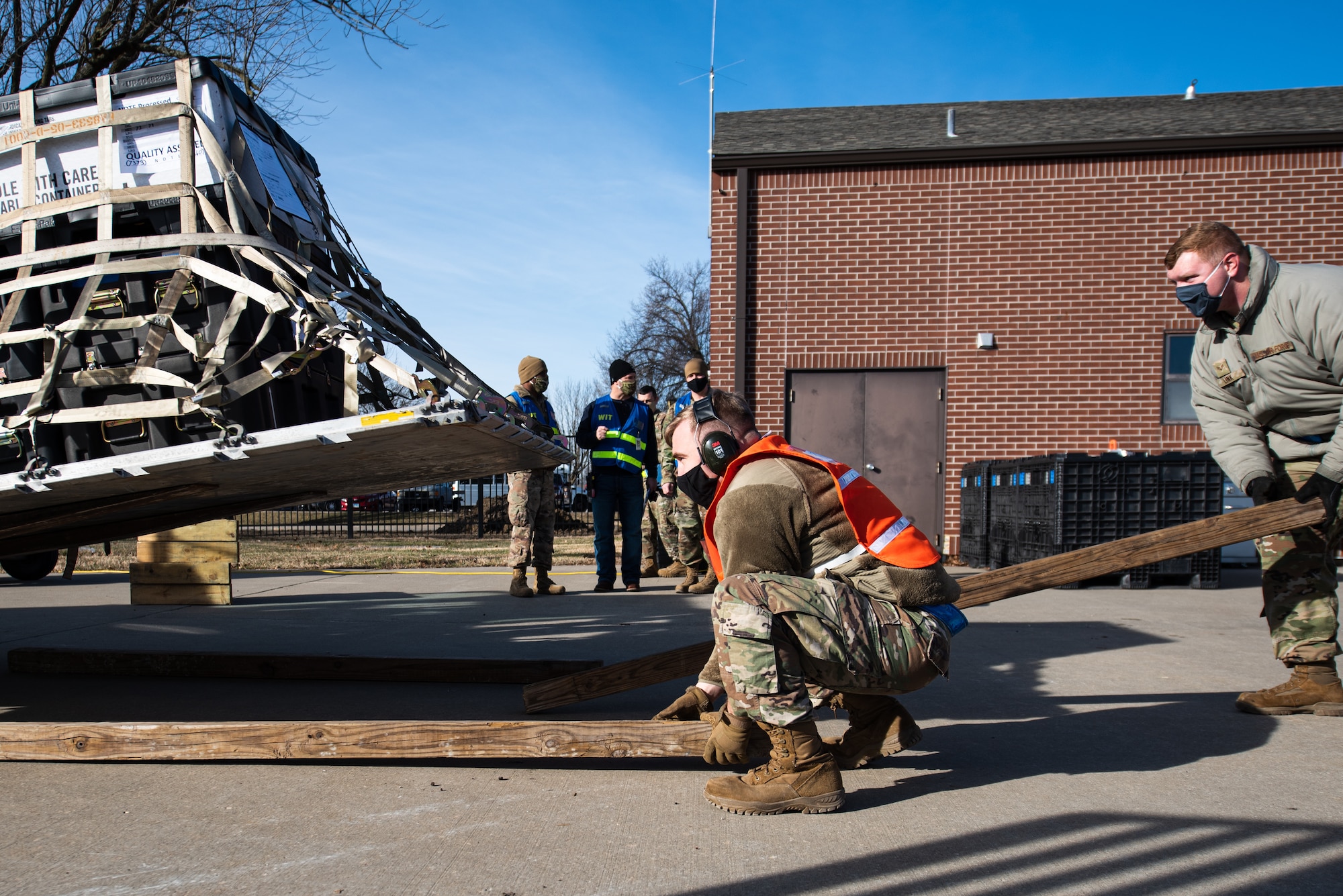 Airmen move wood for cargo palettes