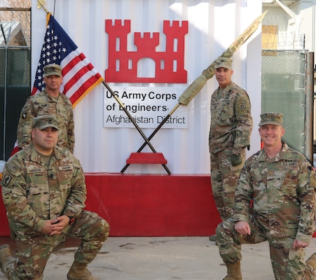 U. S. Soldiers of the U. S. Army Corps of Engineers, Transatlantic Afghanistan District, Bagram Airfield pose in front of the U.S. and USACE command flag after the Casing of the Colors Ceremony. Representing the District are from left, Sergeant First Class Joseph Harrison (kneeling), Sergeant Major Nathan Marshall, Senior Enlisted Leader, COL Mark Geraldi, Afghanistan District Commanding Officer, and Major John Zook (kneeling).