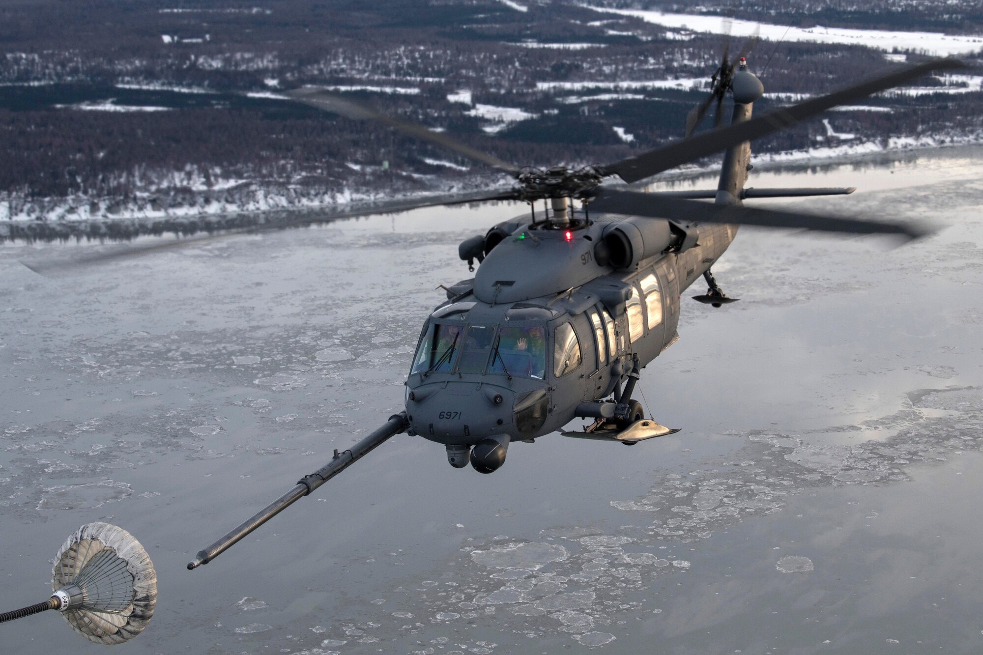 U.S Air Force HH-60 Pave Hawk helicopter assigned to the 210th Rescue Squadron, Alaska Air National Guard, conducts aerial refueling from a U.S. Air Force HC-130J Combat King II assigned to the 211th Rescue Squadron, Alaska Air National Guard, over Alaska, Jan. 21, 2021, during Operation Noble Defender