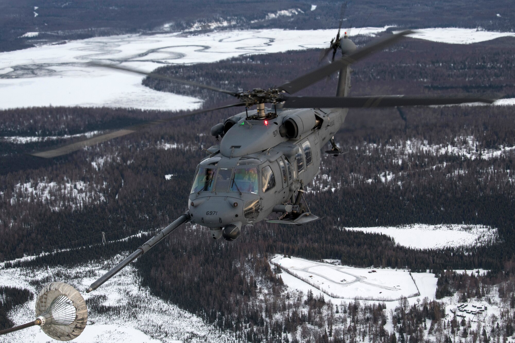 A U.S Air Force HH-60G Pave Hawk helicopter assigned to the 210th Rescue Squadron, Alaska Air National Guard, conducts aerial refueling from a U.S. Air Force HC-130J Combat King II assigned to the 211th Rescue Squadron, Alaska Air National Guard, over Alaska, Jan. 21, 2021, during Operation Noble Defender. Operation Noble Defender is a North American Air Defense Command air-defense operation which allows dynamic training for operational readiness in an arctic environment.