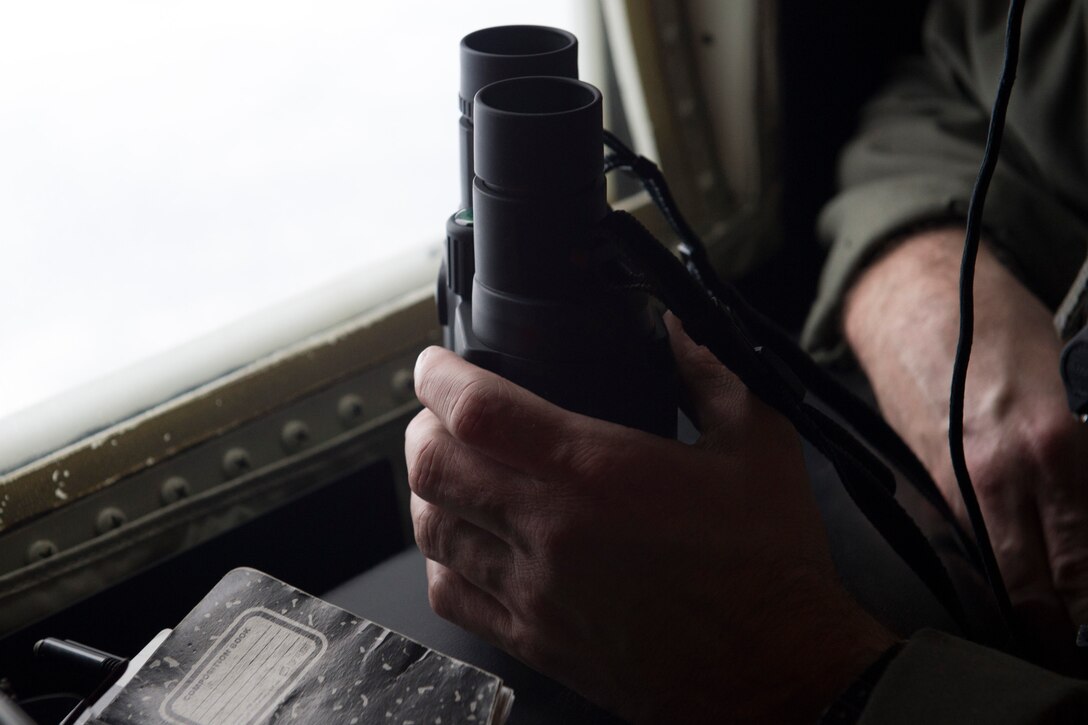 U.S. Air Force Tech. Sgt. Eric Dickerson, a loadmaster assigned to the 211th Rescue Squadron, Alaska Air National Guard, looks for a simulated search-and-rescue target over Alaska, Jan. 21, 2021, during Operation Noble Defender. Operation Noble Defender is a North American Air Defense Command air-defense operation which allows dynamic training for operational readiness in an arctic environment.