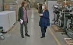 Two women chat in a warehouse.