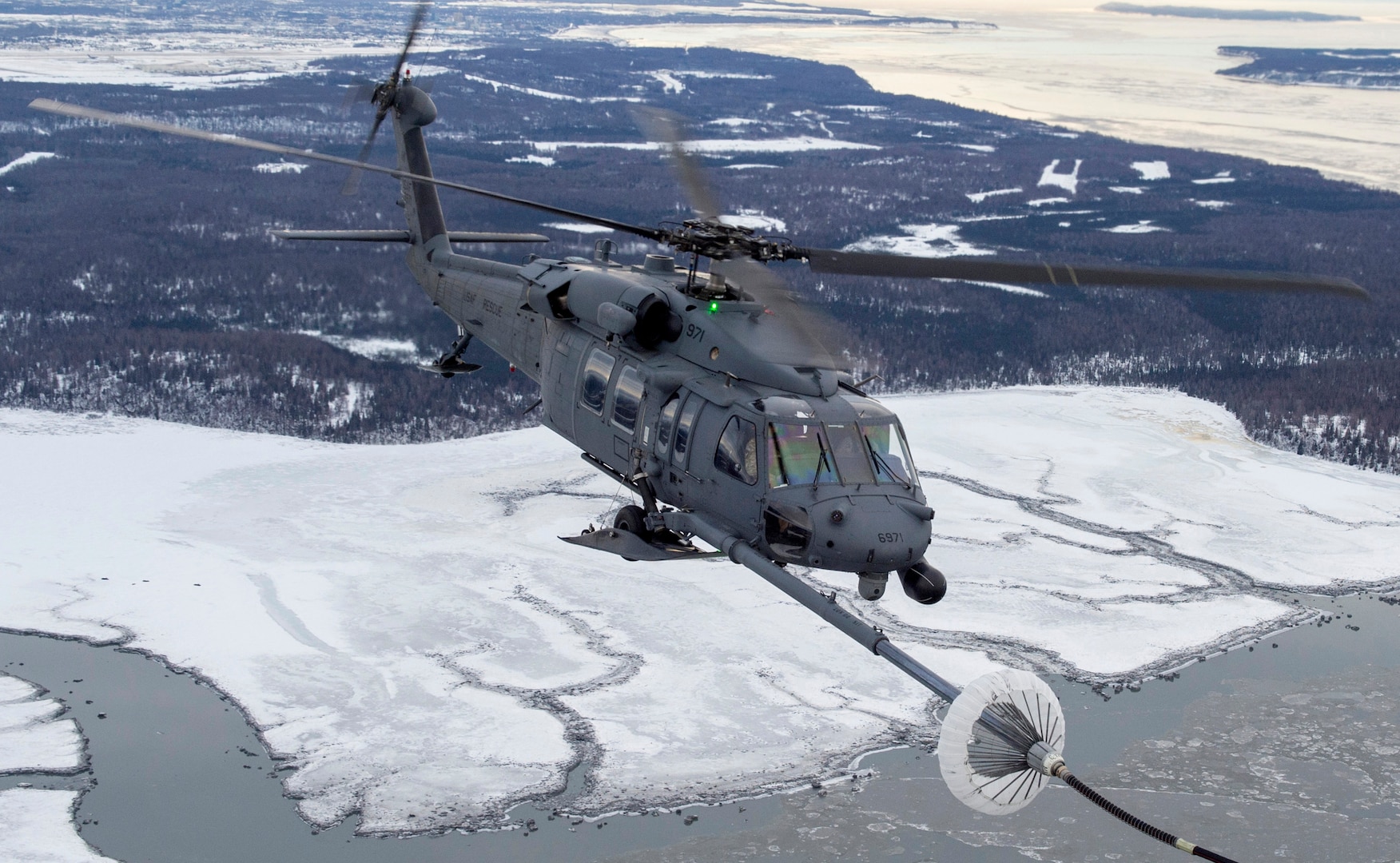 A U.S Air Force HH-60G Pave Hawk helicopter assigned to the 210th Rescue Squadron, Alaska Air National Guard, conducts aerial refueling from a U.S. Air Force HC-130J Combat King II assigned to the 211th Rescue Squadron, Alaska Air National Guard, over Alaska, Jan. 21, 2021, during Operation Noble Defender. Operation Noble Defender is a North American Air Defense Command air-defense operation that allows dynamic training for operational readiness in an Arctic environment.