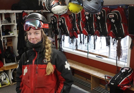 A woman wearing ski gear is surrounded by ski gear