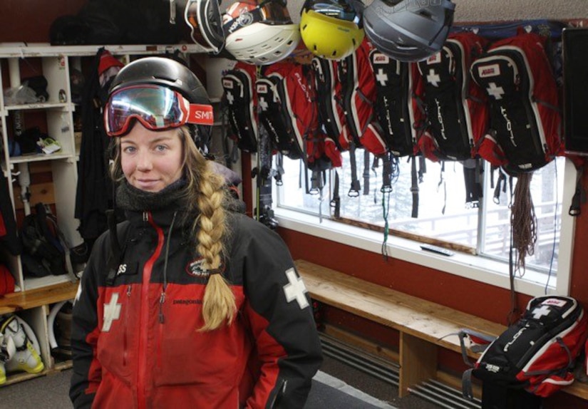 A woman wearing ski gear is surrounded by ski gear