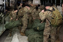 Soldiers with the Vermont National Guard's 172nd Law Enforcement Detachment unload a bus at Burlington International Airport in South Burlington, Vermont, Jan. 26, 2021. The detachment is deploying to the U.S. European Command area of responsibility to support Operation Freedom's Sentinel. (U.S. Army National Guard photo by Don Branum)