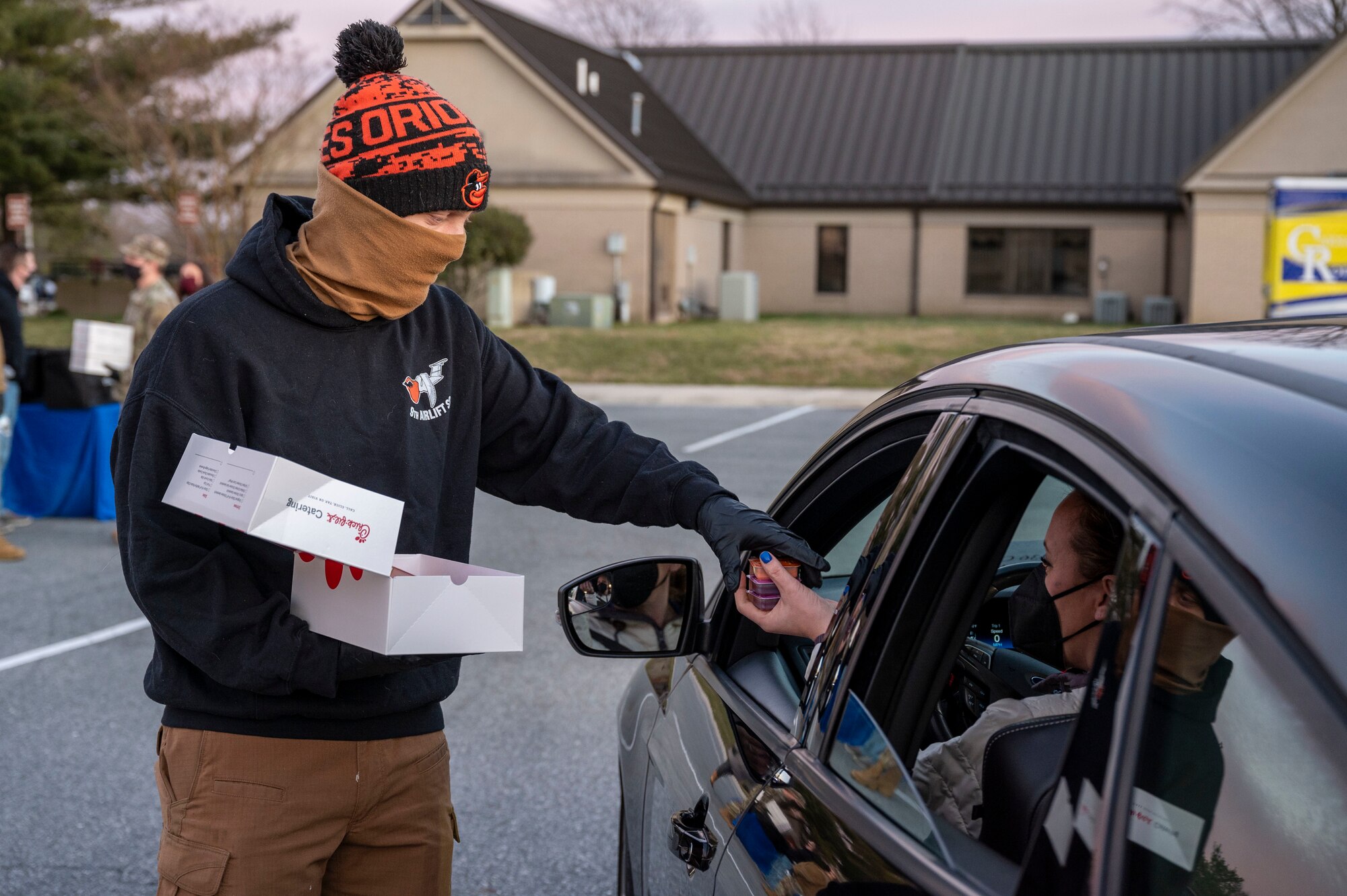 Staff Sgt. Justin Thomas, 9th Airlift Squadron loadmaster, hands out sauce packets at a deployed spouses drive-thru dinner event Jan. 21, 2021, at Dover Air Force Base, Delaware. The event provided meals, gift bags and toys to families of deployed service members in recognition of their sacrifice. The deployed spouses dinner is one of many ways Team Dover takes care of service members and their loved ones. (U.S. Air Force photo by Airman 1st Class Cydney Lee)