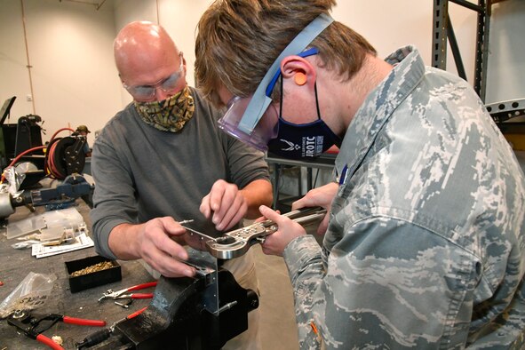 Darrel Gronau (left), aviation structure repair instructor, teaches Connor Innocenzi, Utah Military Academy student, proper riveting technique on part of an aircraft fuselage skin.