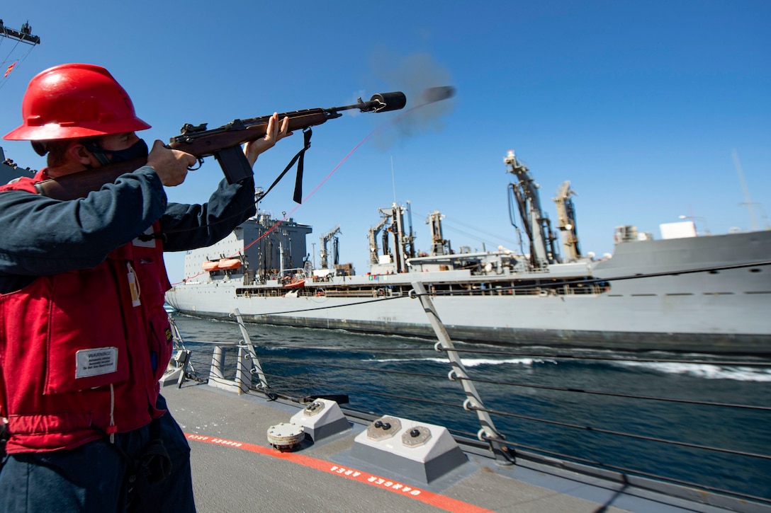 A sailor fires a shot from a ship to another ship at sea.