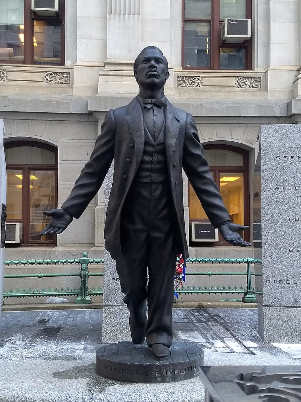 A statue shows a man leaning forward with his arms outstretched.