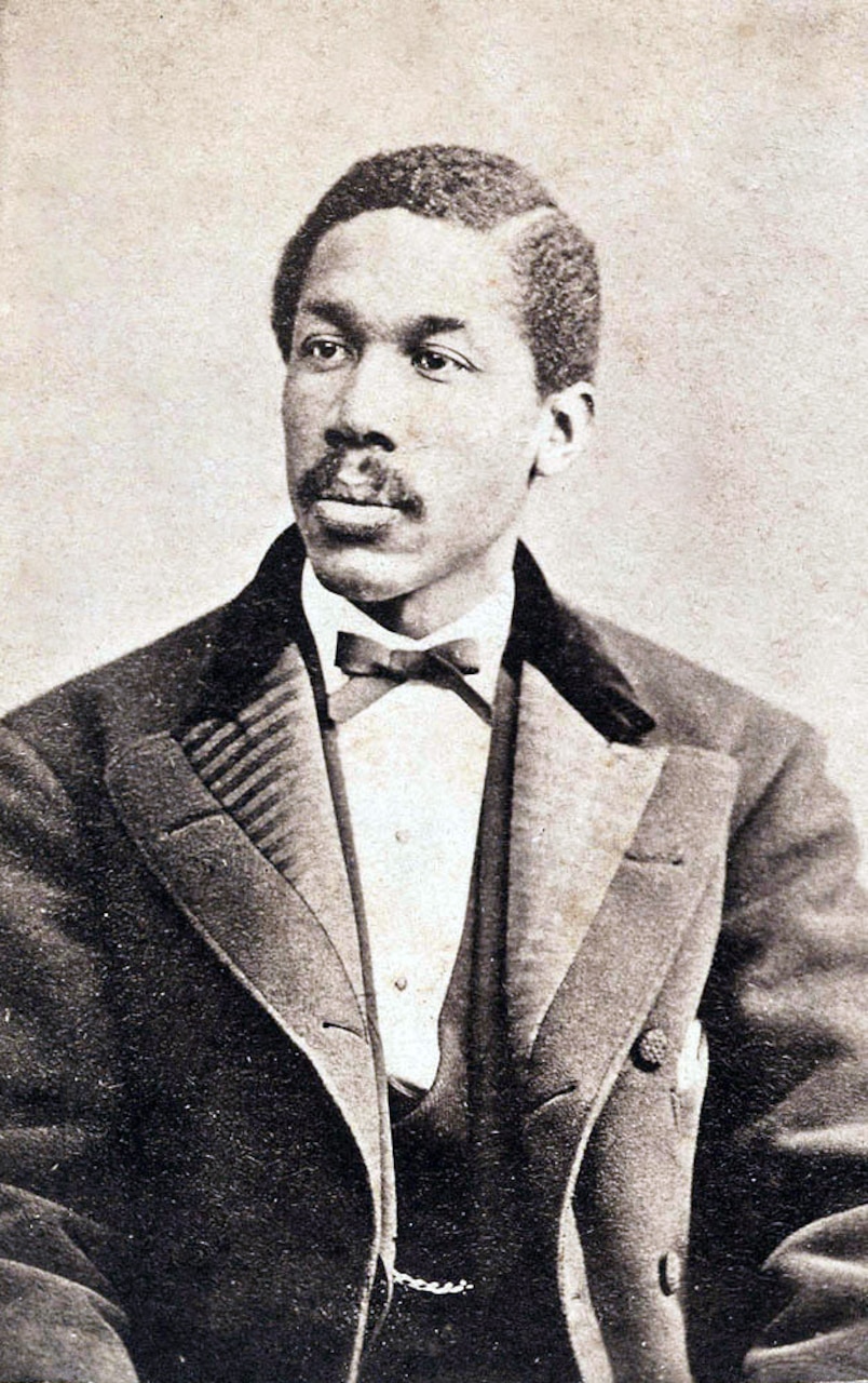 In a photo from the 1800s, a man dressed in a suit poses for the camera.