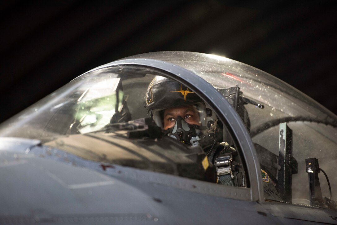 A pilot sits in a cockpit.