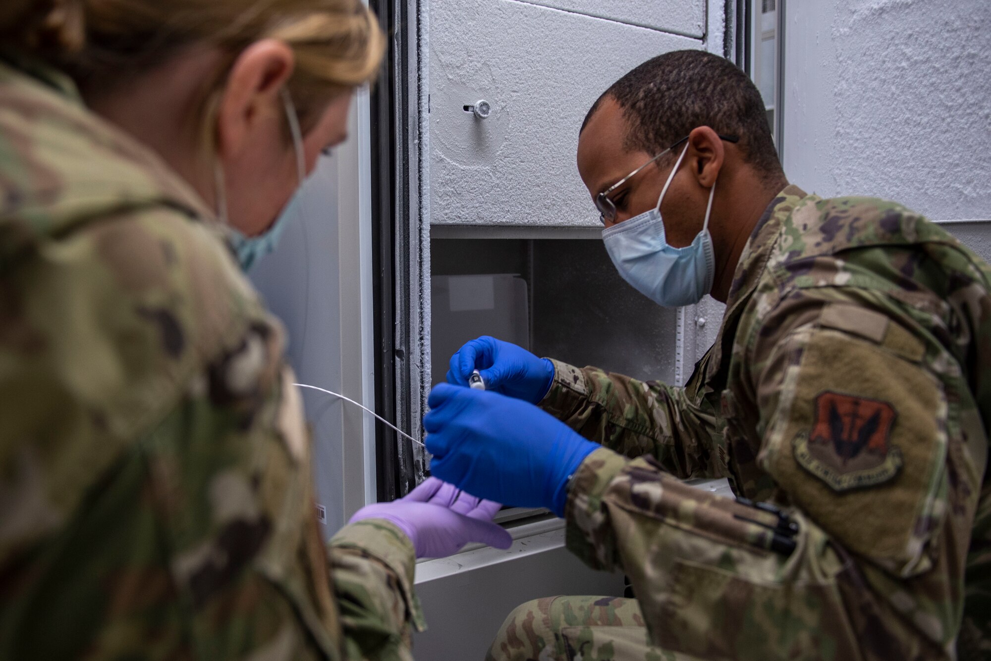 Tech Sgt. Johnmarth Perez, 4th Healthcare Operation Squadron medical support services flight chief (right), and Staff Sgt. Samantha Cartwright, 4th HOS immunizations technician (left), remove vials of COVID-19 vaccines from a freezer onto a carrier for transport at Seymour Johnson Air Force Base, North Carolina, Jan. 14, 2021.