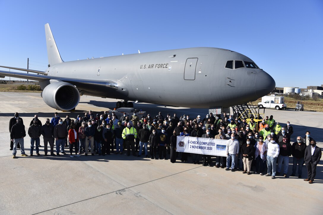 Photo of a group standing in front of an airplane