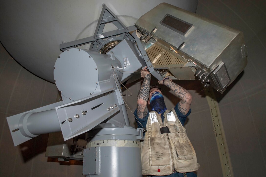 A man works on a satellite dish console.