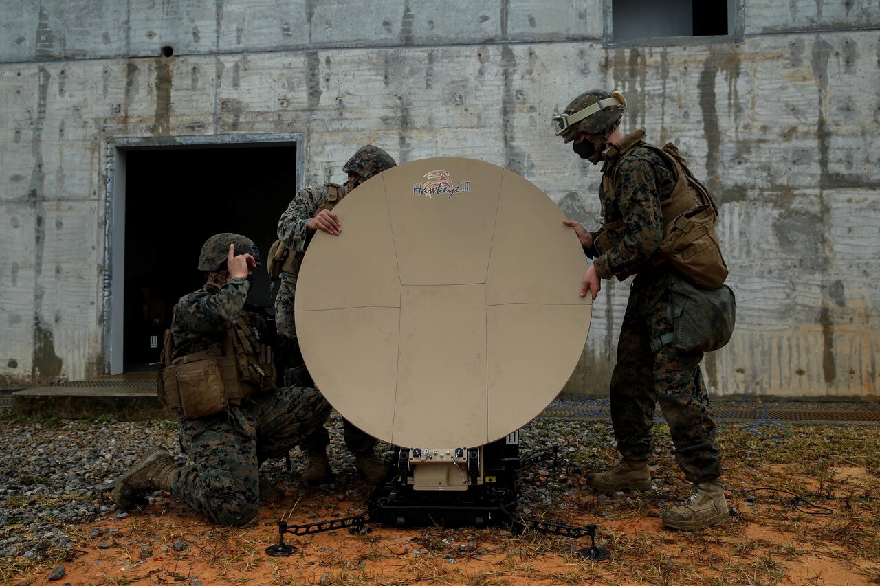 Three Marines set up a satellite dish.