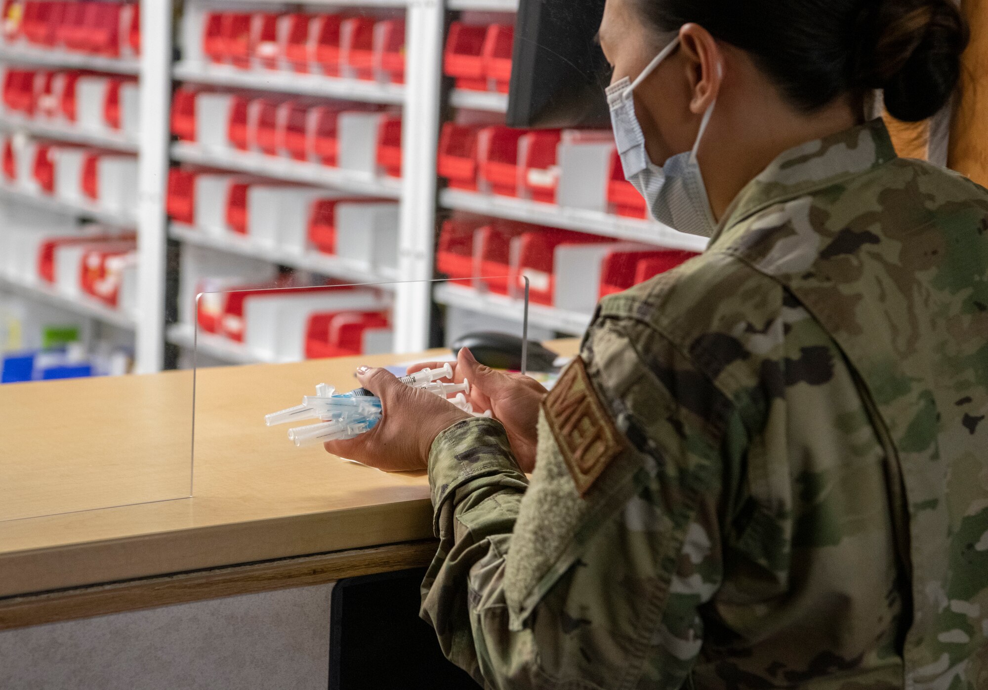 Maj. Suzette Dean, 319th Health Care Operations Squadron family medicine flight commander, carries a handful of syringes filled with the COVID-19 vaccine from the pharmacy to be administered to Airmen at Grand Forks Air Force Base, N.D., Jan. 21, 2021. The COVID-19 vaccine protects against the virus  by producing an immune response within the body.