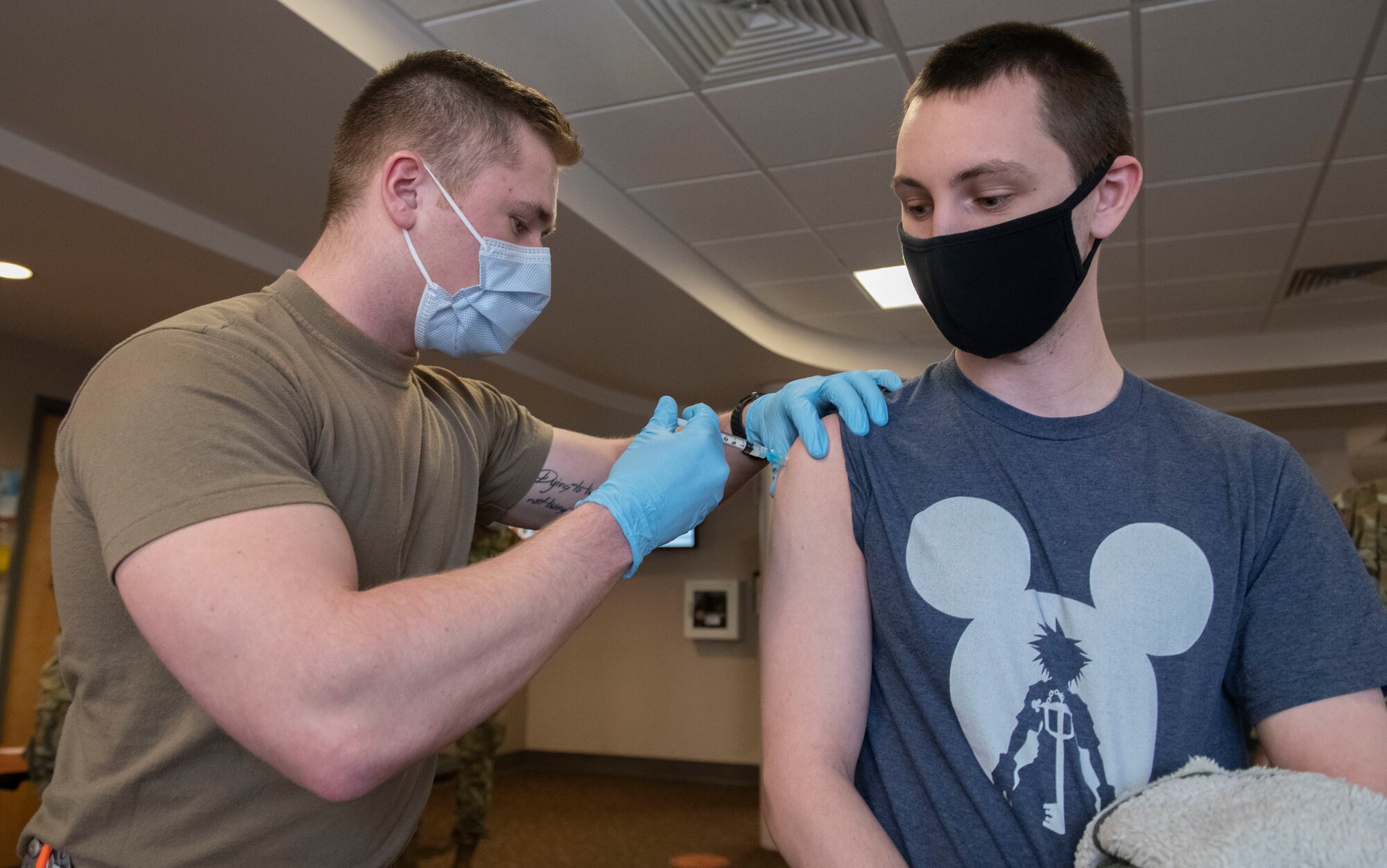 Airman 1st Class Brett Gundon, 319th Health Care Operations Squadron aerospace medical technician, administers a COVID-19 vaccine to Capt. Eric Chistolini, 348th Reconnaissance Squadron RQ-4 Global Hawk mission commander, at Grand Forks Air Force Base, N.D., Jan. 22, 2021. The 319th Reconnaissance Wing received their first shipment of vaccines on Jan. 21 and within 30 hours, all doses had been administered to base personnel.