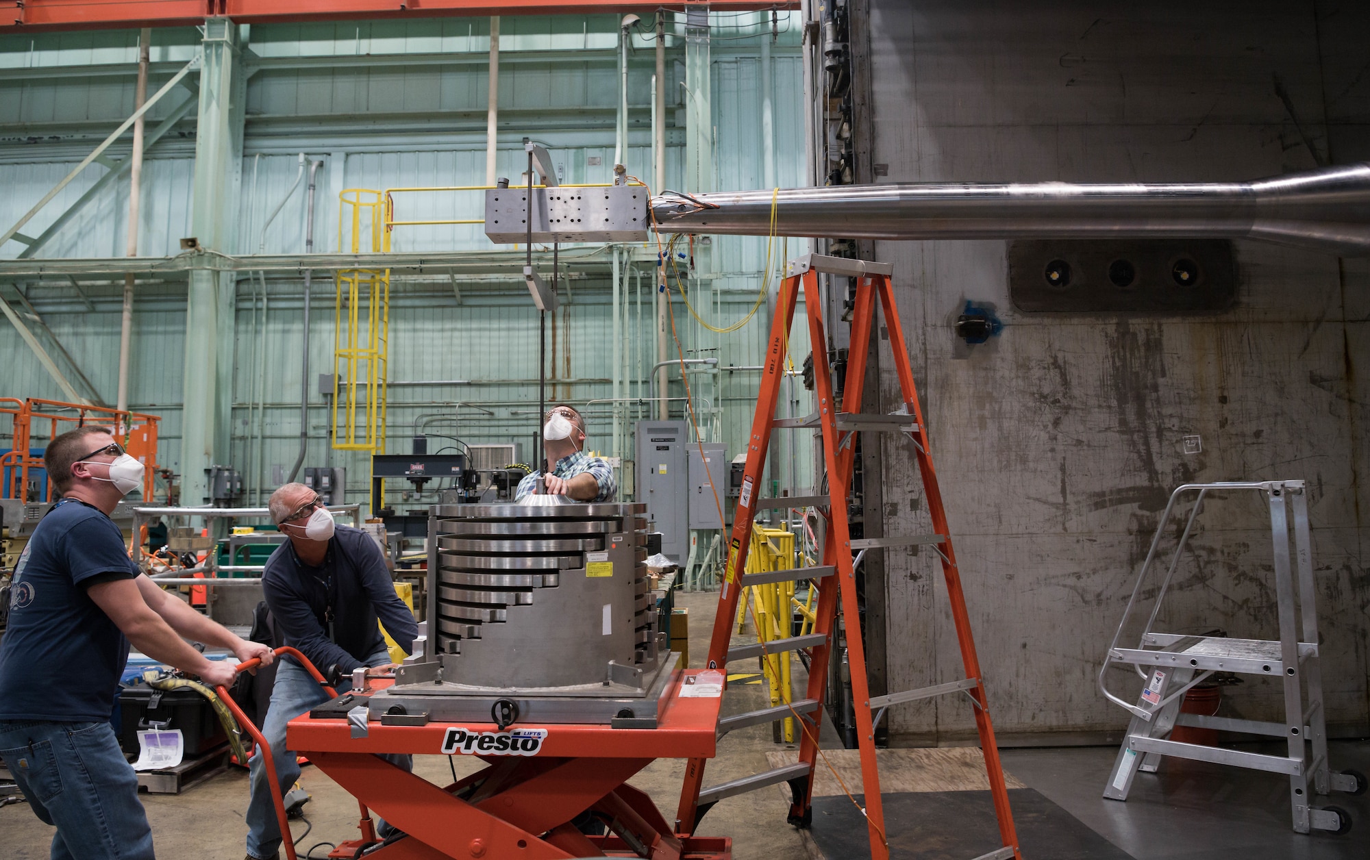 Chris Lawton, from left, outside machinist, Darrell Gagnon, outside machinist, and Bradley Rogers, lead outside machinist, reposition checkload equipment on a balance calibration body as part of the preparations to install a model on the sting, Jan. 4, 2021, at Arnold Air Force Base, Tenn. (U.S. Air Force photo by Jill Pickett) (This image was altered by obscuring a badge for security purposes.)