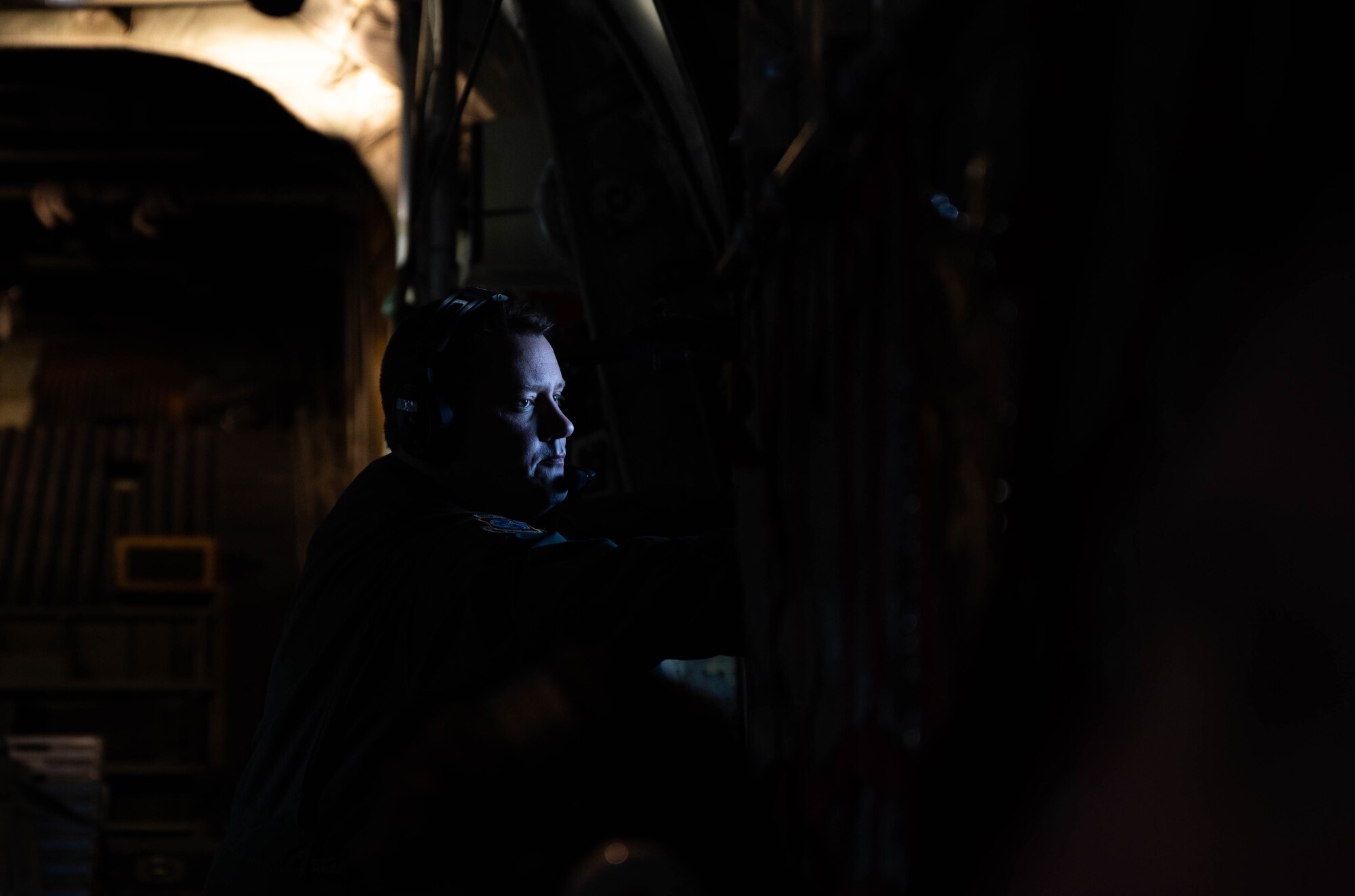 An Airman looks out the window of an aircraft.