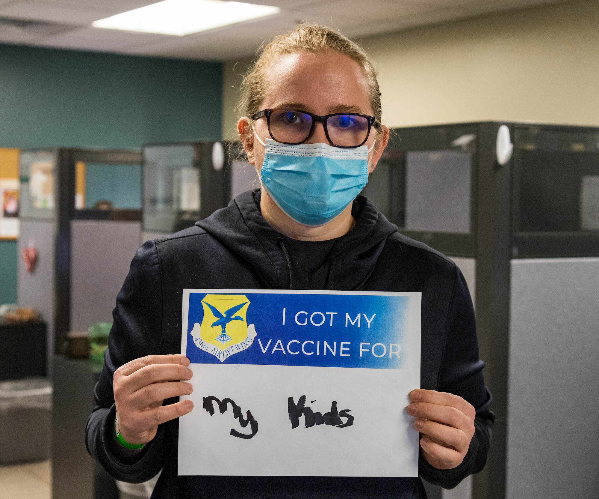 Sarah Carter, Defense Commissary Agency worker, displays a sign stating why she volunteered for the COVID-19 vaccine Jan. 22, 2021, at Dover Air Force Base, Delaware. Carter was among the first Team Dover front-line workers who voluntarily received the vaccine in accordance with Department of Defense guidance. The vaccine was granted emergency use authorization by the U.S. Food and Drug Administration for use in prevention of COVID-19. (U.S. Air Force photo by Roland Balik)