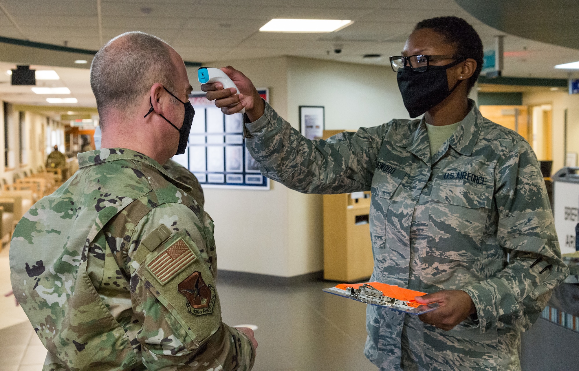 Chief Master Sgt. Jeremiah Grisham, 436th Airlift Wing interim command chief, has his temperature taken by Airman 1st Class Daija Norwood, 436th Operational Medical Readiness Squadron dental assistant, after entering the 436th Medical Group Clinic Jan. 20, 2021, at Dover Air Force Base, Delaware. Grisham was among the first Team Dover senior leaders who voluntarily received the COVID-19 vaccine in accordance with Department of Defense guidance. The vaccine was granted emergency use authorization by the U.S. Food and Drug Administration for use in prevention of COVID-19. (U.S. Air Force photo by Roland Balik)