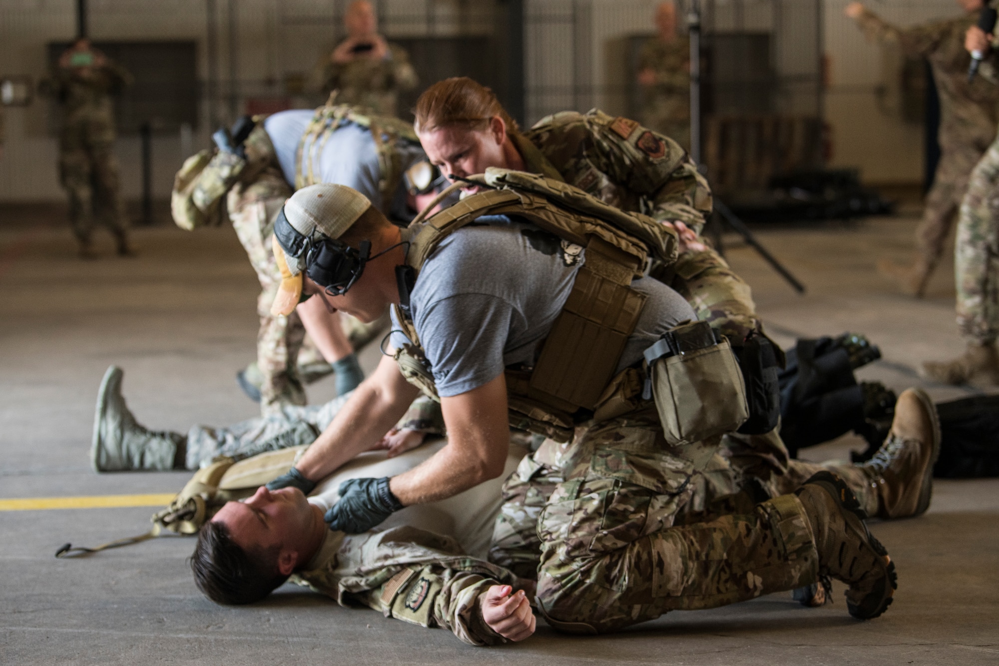 An Airman pretends to check for a pulse on another Airman simulating injuries