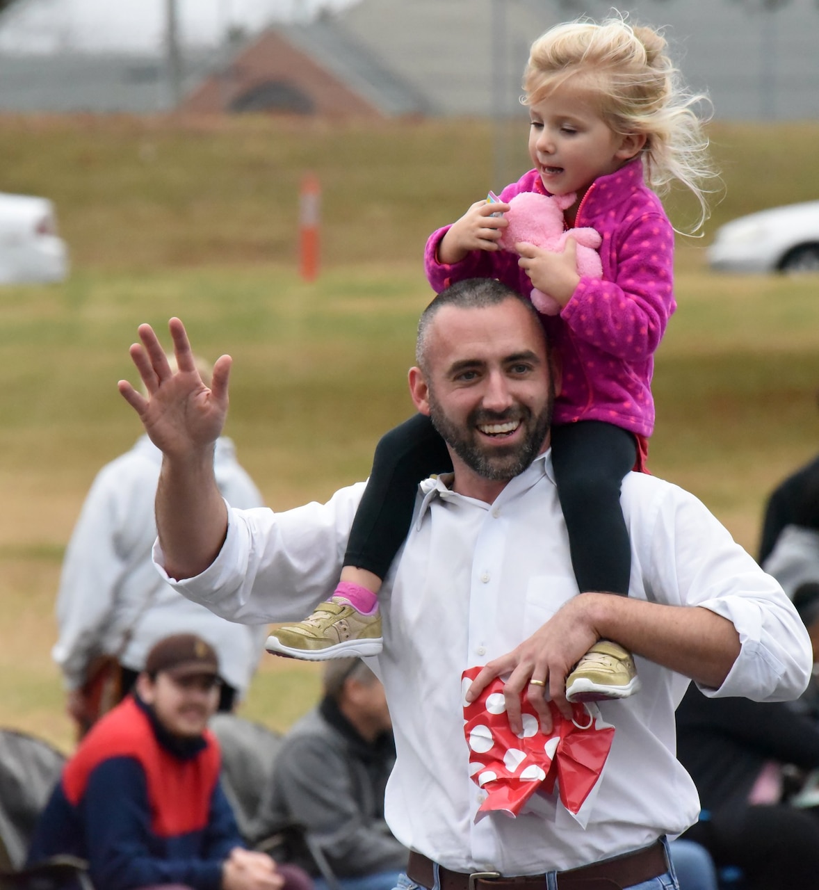 A man gives a small girl a piggyback ride on his shoulders.