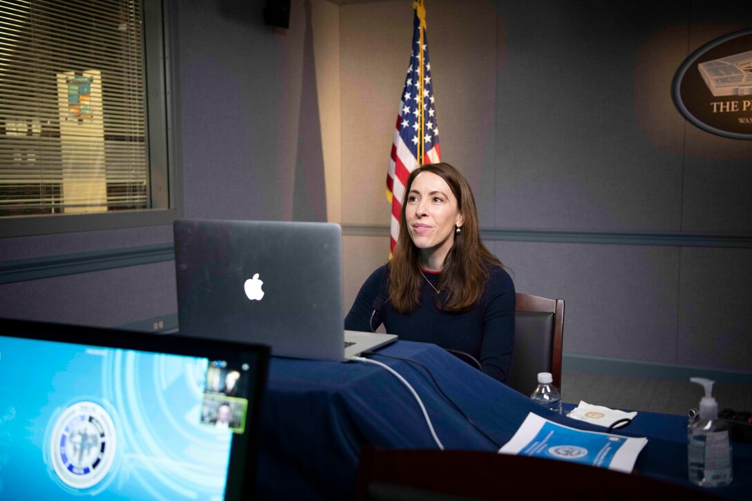 A woman seated at a computer speaks.